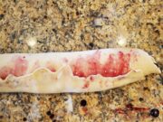 Dough with blueberry sauce inside resting on countertop.