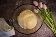 Dough in greased bowl with some tulips beside it.