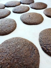 Chocolate whoopie pies baked on parchment paper.
