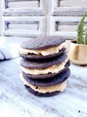 Chocolate whoopie pies with peanut butter icing with a kitchen towel and a cactus in the background.